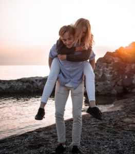 Woman piggyback on man on beach