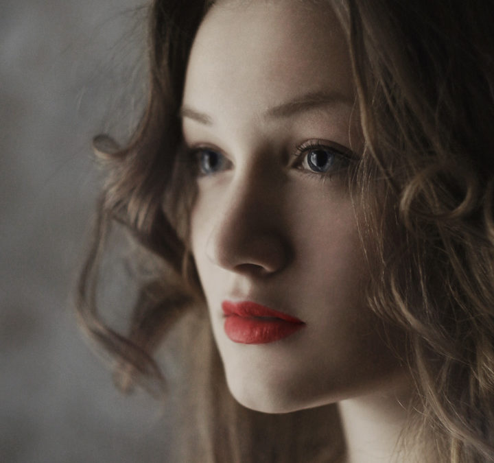 Young woman's face with red lipstick and white skin, a serious look forward