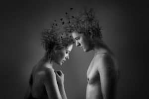 Naked man and woman facing each other with heads bowed, birds flying from their heads that are made of plants