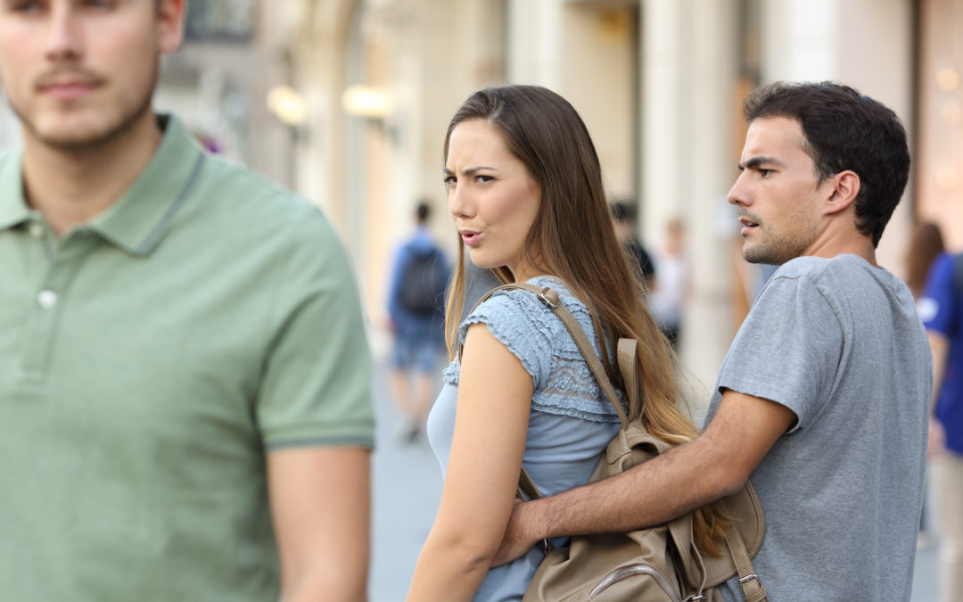 Woman leering amorously at another man on the street as her distraught boyfriend holds her back