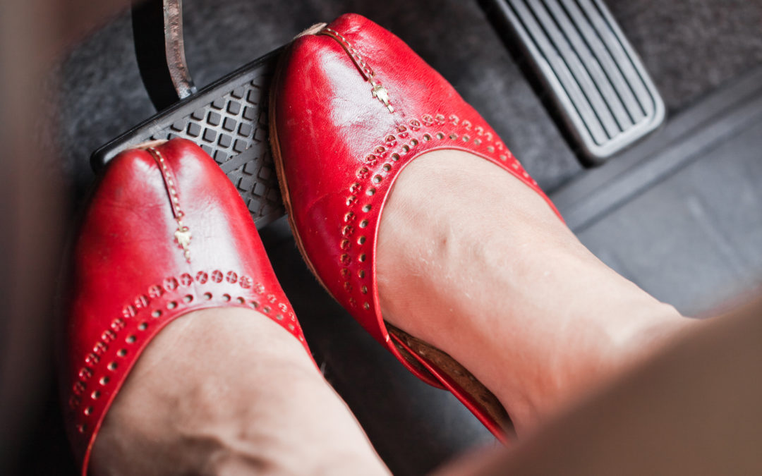 Woman's right and left shoe on car brake pedal with top of feet exposed