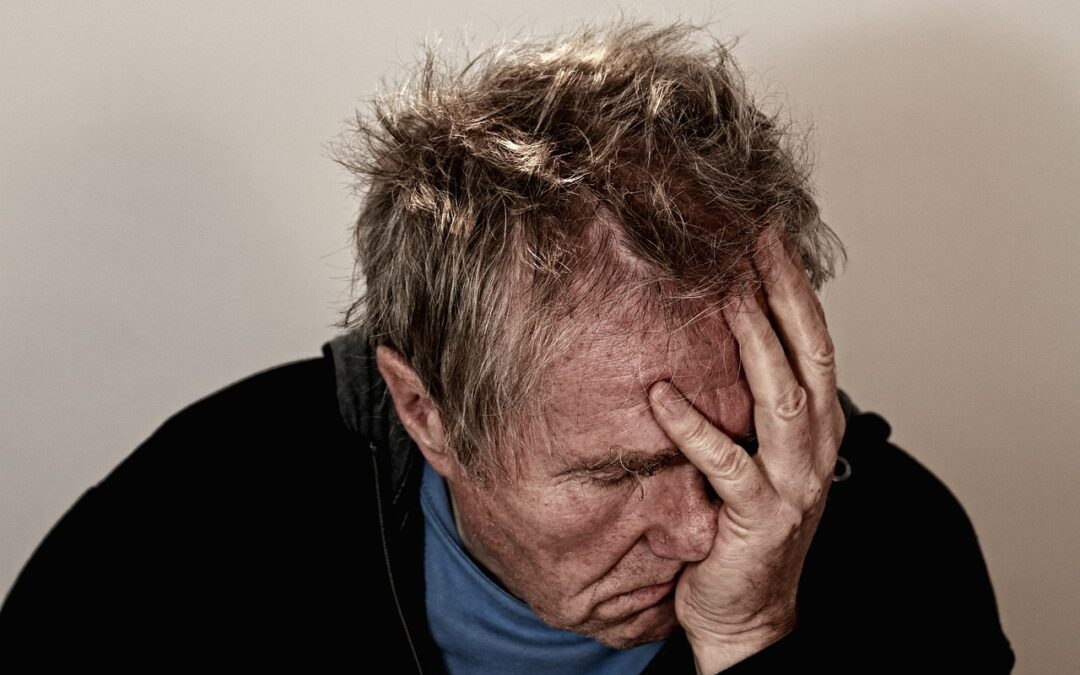 older man, face buried in hands